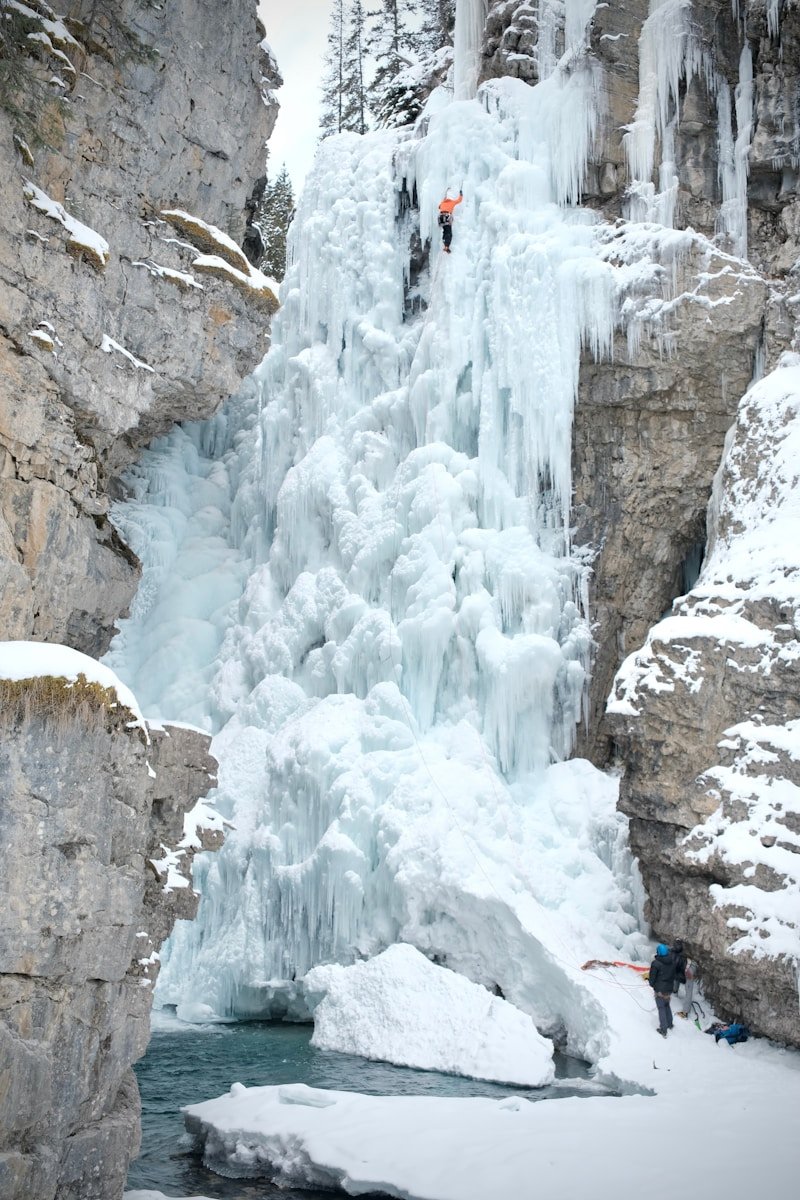 A man standing in front of a frozen waterfall