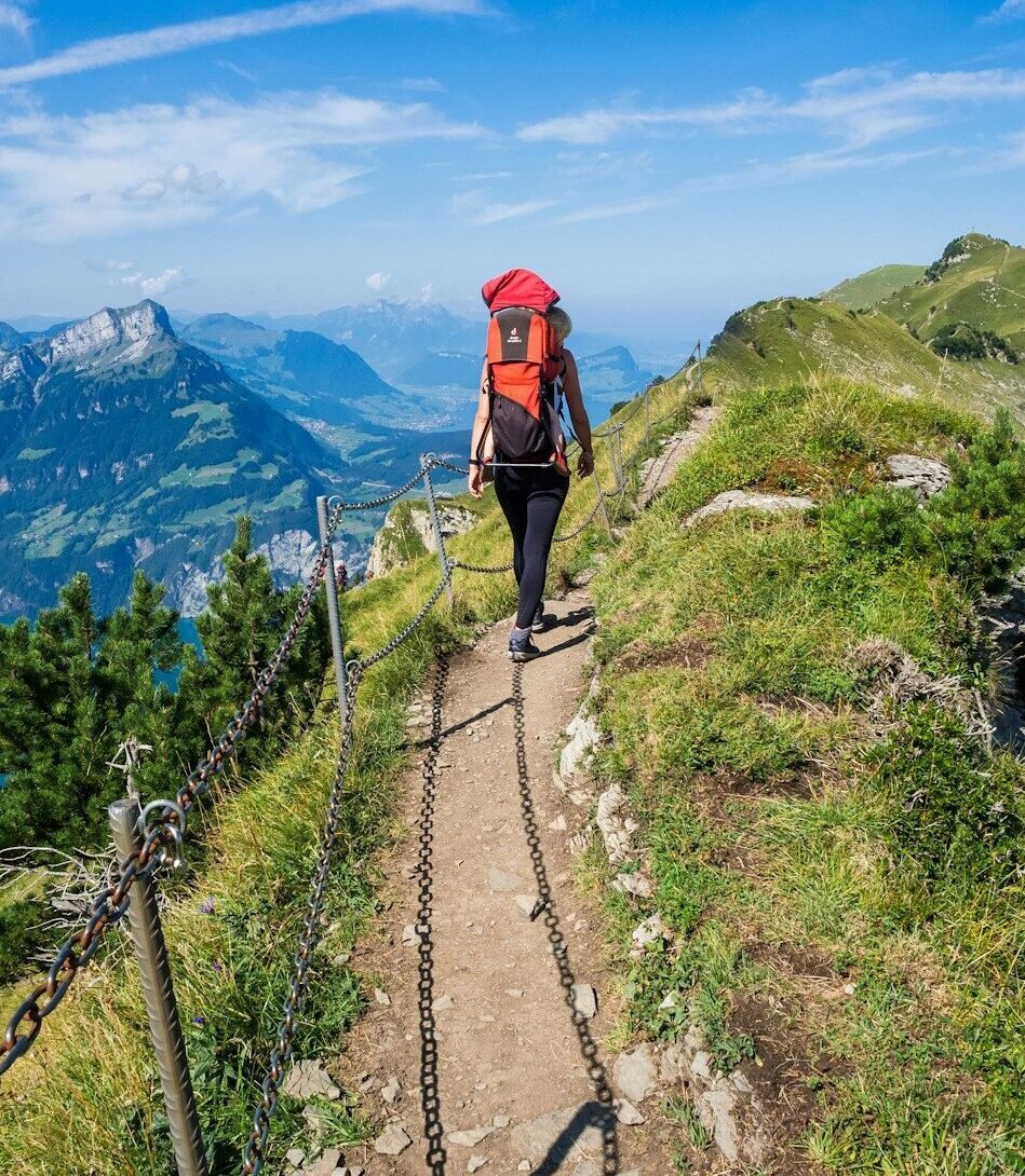 man in red jacket walking on pathway during daytime